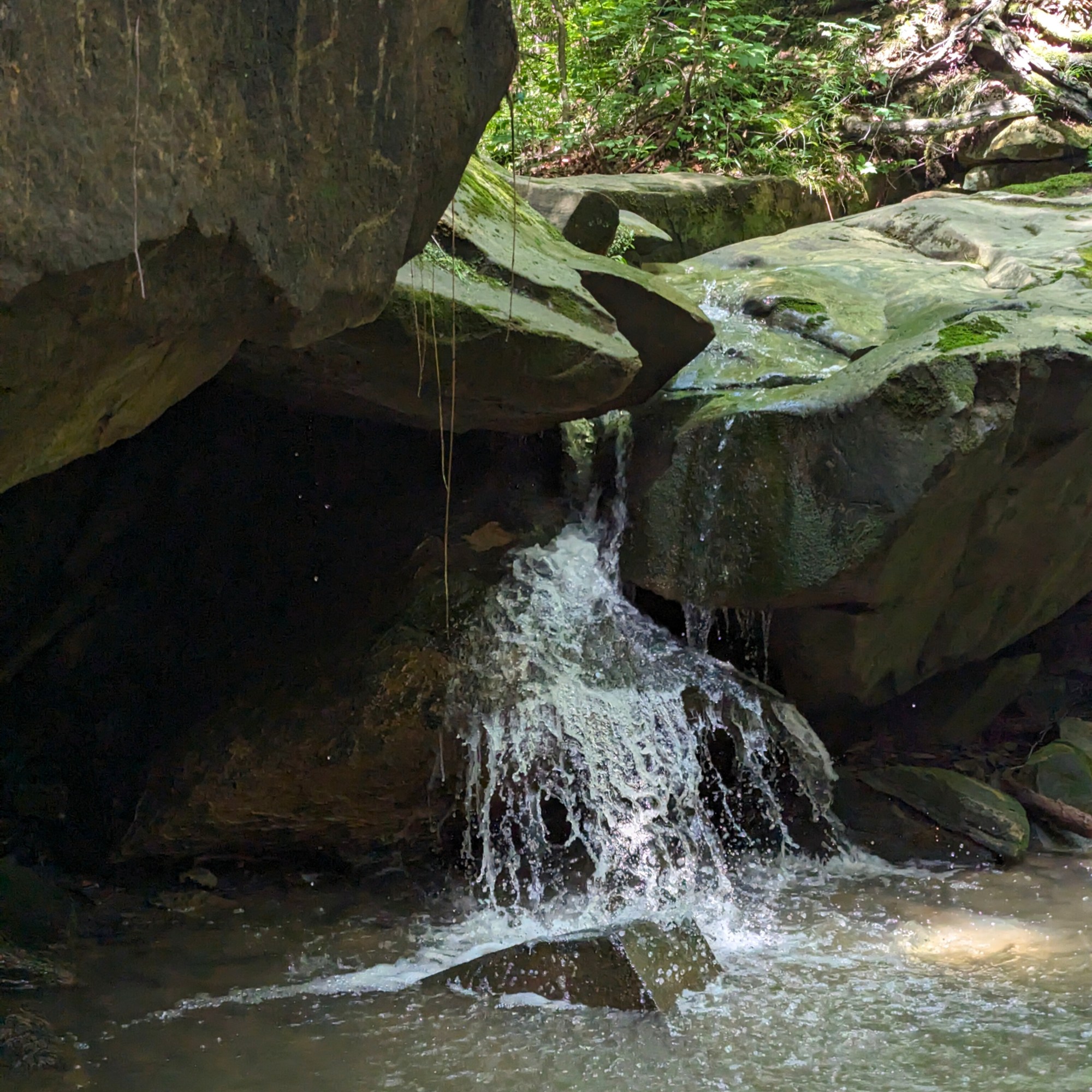 Waterfall falling between two large overhanging rocks